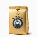 Ocean City Yacht Club gold metallic clutch bag with anchor charm and chain strap